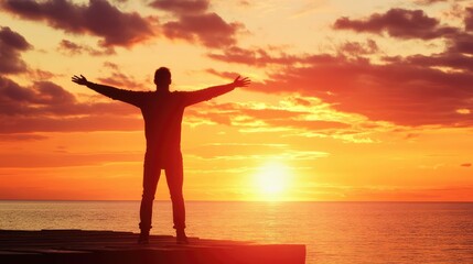 Fototapeta premium Man stands with outstretched arms on a pier at sunset, celebrating freedom and success by the ocean.