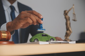 Judge gavel and miniature car symbolize auction or court case against driver who has accident and receiving vehicle insurance payment be on table in front of hands of lawyers. Selective focus