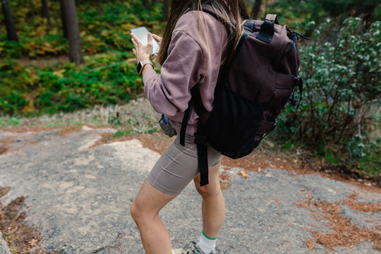 Unknown female athlete uses her smartphone to visualize a hiking route