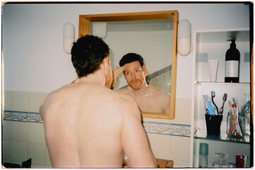 Film lit with flash of adult male finishing a daily skin care routine