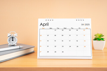 April 2025, Monthly desk calendar for 2025 year on wooden table.