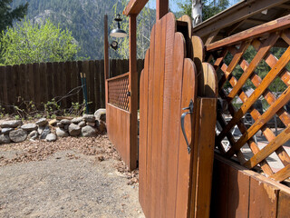 Beautiful view of an open wooden gate leading into a lush, green backyard on a sunny day