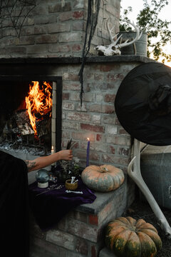 woman decorates outdoor fireplace in witch them for halloween