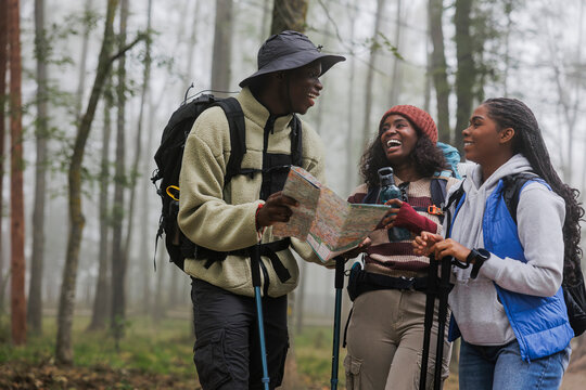 Group of friends hiking and navigating in forest using map