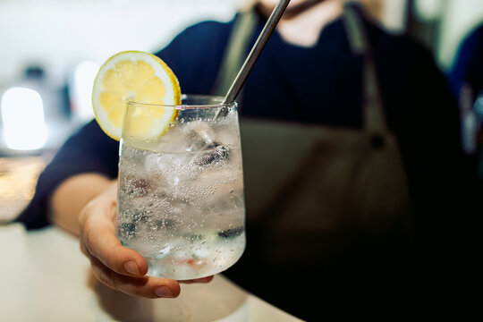 Bartender serving a sparkling drink with lemon slice