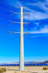 A tall power pole stands in a field with a clear blue sky above