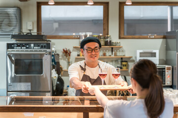 ワインを出す飲食店・居酒屋のスタッフと受け取るホールスタッフの女性
