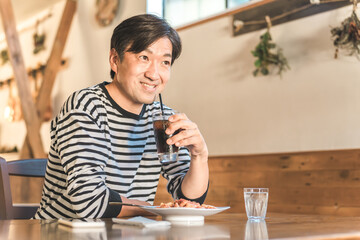 お昼休みにカフェやレストランでランチ・食事をするアジア人の男性
