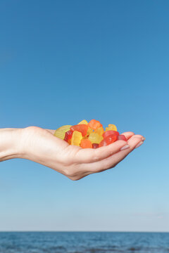 Hand Holding Colorful Gummy Candies by the Ocean
