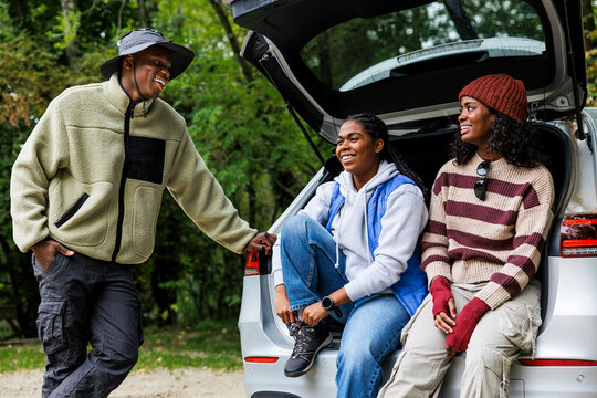 Friends preparing for hiking trip in forest talking and laughing