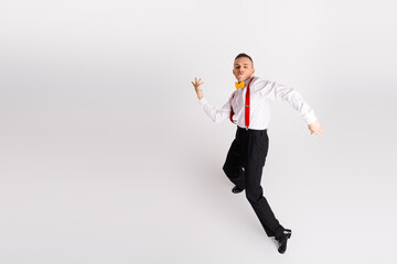 Young dancer in elegant fashion performs energetic dance moves against white background