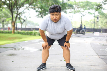 Exhausted Young Overweight Male Doing Jogging And Take A Break in The Park