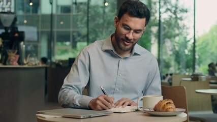 Indian businessman Arabian man guy male business entrepreneur employee student writing in notebook studying in cafe customer write notes freelancer work learn tasks answer mobile call message reading