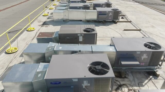 High-definition drone video showcasing multiple HVAC systems installed on a commercial rooftop in an urban setting.