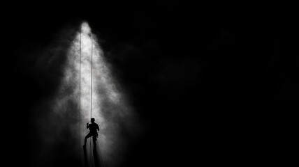 Fototapeta premium Silhouette of climber ascending in dark, smoky environment