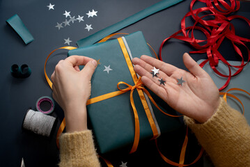 Woman decorates Christmas gift with stars
