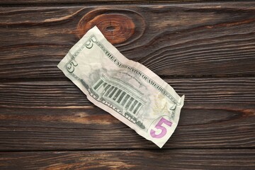 One crumpled dollar banknote on wooden table, top view