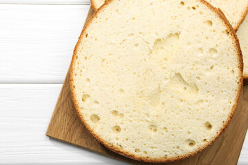 Delicious cut sponge cake on white wooden table, flat lay