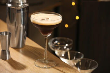 Glass with delicious espresso martini on wooden table in bar