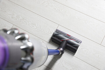 Cleaning floor with cordless vacuum cleaner indoors, closeup
