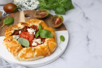 Tasty galette with tomato, basil and cheese on white marble table, closeup. Space for text