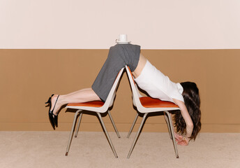 Woman Balancing on Two Chairs with Coffee on Back