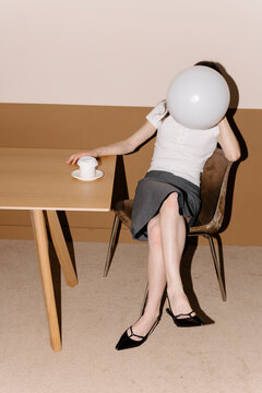 Woman Sitting with Balloon Over Face in Office Setting