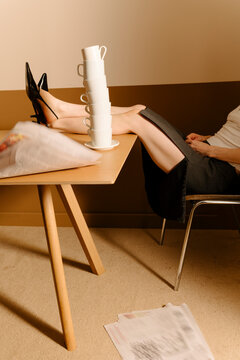 Relaxed Office Worker Balances Coffee Cups on Desk