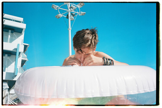 Teen blowing up inflatable pool float outdoors