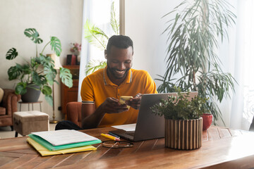 Smiling Man Using Phone And Computer Indoors