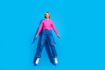 Full size photo of pretty young woman jump empty space wear pullover isolated on blue color background