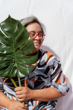 Woman with down syndrome holding a monstera deliciosa leaf