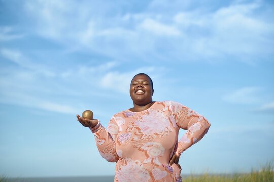 Happy woman with a golden ball on shore