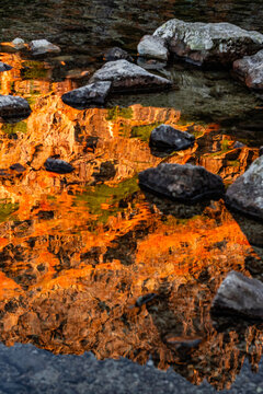 Reflection of sunset golden mountains in cold water