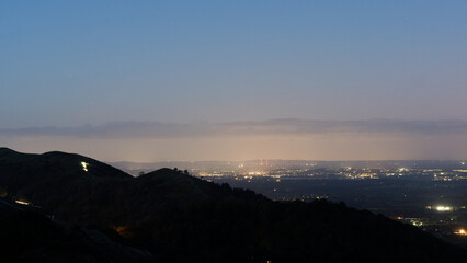 On a hill above a landscape of hills and a city in the distance