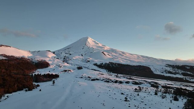 Snow-capped volcano Llaima and forested plains in clear sunlight
