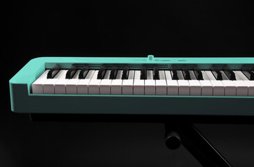 Turquoise synthesizer on black background. Electronic musical instrument