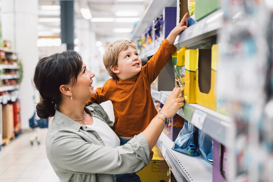 Mother helping her son reach for a product on a grocery store shelf