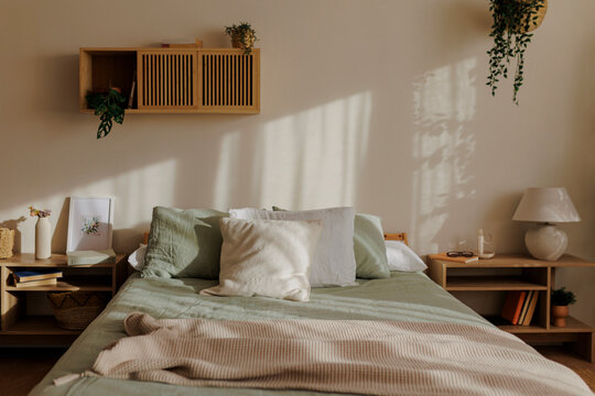 Sun shining on bed with green sheets in modern bedroom