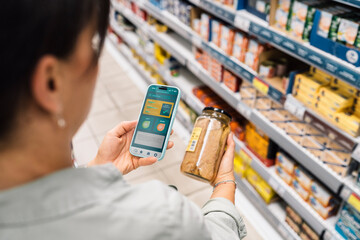 Woman using smartphone app to check product information at grocery sto