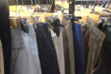Thrifting's vibrant collection of sweaters, shirts, hoodies, trousers and knitted t-shirts are elegantly displayed on wooden hangers, featuring a variety of colors and textures.