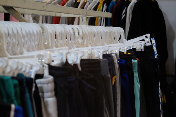 Thrifting's vibrant collection of sweaters, shirts, hoodies, trousers and knitted t-shirts are elegantly displayed on wooden hangers, featuring a variety of colors and textures.