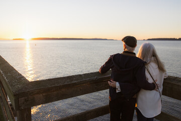 Elderly Couple Watching Sunset by the Ocean