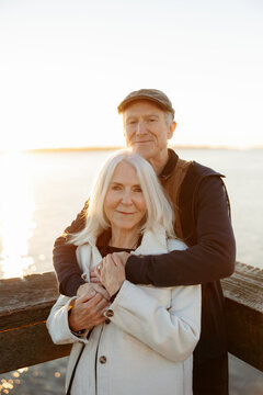 Senior Couple Embracing by Peaceful Lakeside Sunset