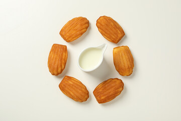 Madeleine cakes and cream on white background, top view