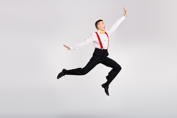 Young dancer in a vintage outfit performs an energetic jump against a white background, showcasing graceful motion and joyful expression