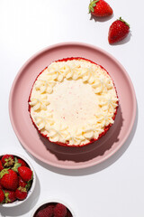 Red velvet cake on pink plate and berries on white background, top view