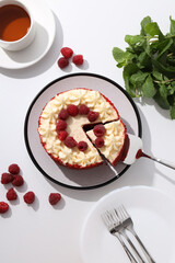 Red velvet cake, cup of tea, mint and berries on white background, top view