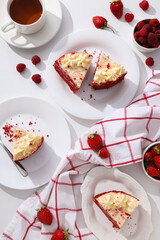 Pieces of red velvet cake on plates, berries and towel on white background, top view