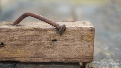 rusty nail in a piece of weathered wood in close-up view, nail is bent at an angle soft focus with blurry background and copy space